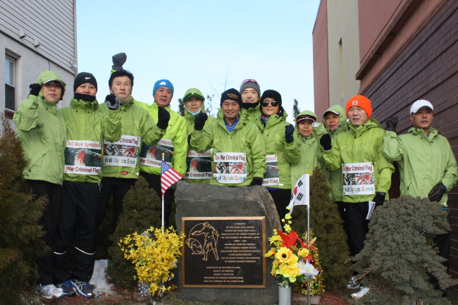 Runners pose around a memorial in memory of comfort women in New York, Sunday, before starting a marathon organized by the Citizens Against War Criminal Symbolism in hopes of banning the Rising Sun Flag, a symbol of Japanese militarism.   Yonhap News