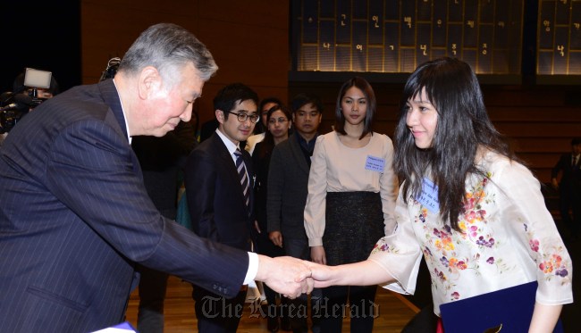 Booyoung Group chairman Lee Joong-keun (left) awards a scholarship to a student at a ceremony in Seoul on Monday.   Park Hae-mook/The Korea Herald
