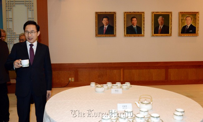 President Lee Myung-bak stands before the portraits of former presidents at Cheong Wa Dae before his last Cabinet meeting Tuesday.   Chung Hee-cho/The Korea Herald
