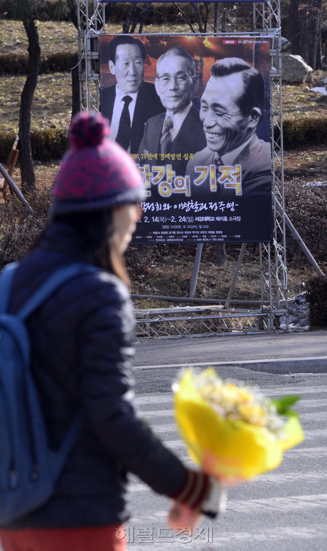 박근혜 18대 대통령 취임식을 앞두고 박 당선인 모교인 서강대에서 박정희 전 대통령을 소재로 한 연극이 공연되고 있어 사회적으로 논란이 일고 있는 가운데 21일 오전 서울 마포구 신수동 서강대에서 2013학년도 신입생 입학식이 치뤄지고 있다. 박해묵 기자/mook@heraldcorp.com
A poster of a play titled “The Miracle of the Han River” is erected at Sogang University, President-elect Park Geun-hye’s alma mater, Thursday. It shows photos of her father, former President Park Chung-hee (from right), Samsung Group founder Lee Byung-chull and Hyundai Group founder Chung Ju-yung.   Park Hae-mook/The Korea Herald