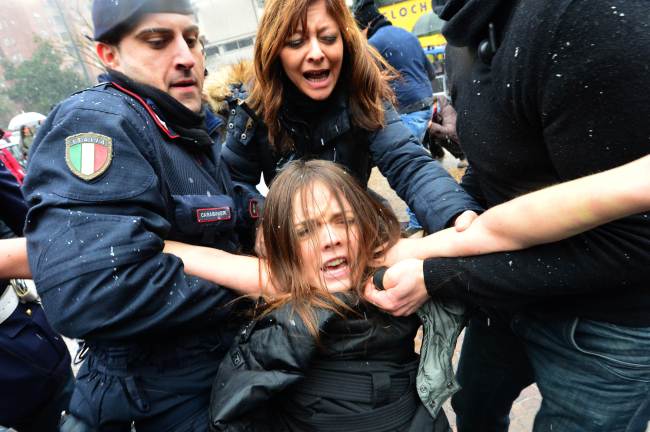 A protester is arrested by riot policemen outside the polling station where former Prime Minister Silvio Berlusconi cast his ballot in Milan on Sunday.   AFP-Yonhap News