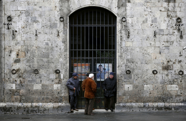 Pedestrians stand and chat outside a shuttered branch of Intesa Sanpaolo SpA bank in Siena, Italy.   Bloomberg