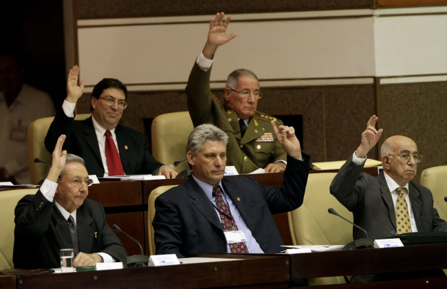 Cuba’s new Vice President Miguel Diaz-Canel (center, front row), Cuba’s President Raul Castro (left), Vice President Jose Ramon Machado Ventura (right) raise their hands to vote during the closing session at the National Assembly in Havana on Sunday.   AP-Yonhap News