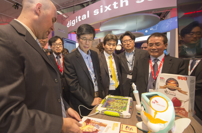 SK Telecom CEO Ha Sung-min (left) looks at educational robot “Atti” unveiled by the company at the Mobile World Congress on Monday.
Joint Press Corps
