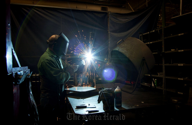 A worker welds a 5-gallon ram at the Graco Inc. manufacturing facility in Minneapolis, Minnesota.   Bloomberg