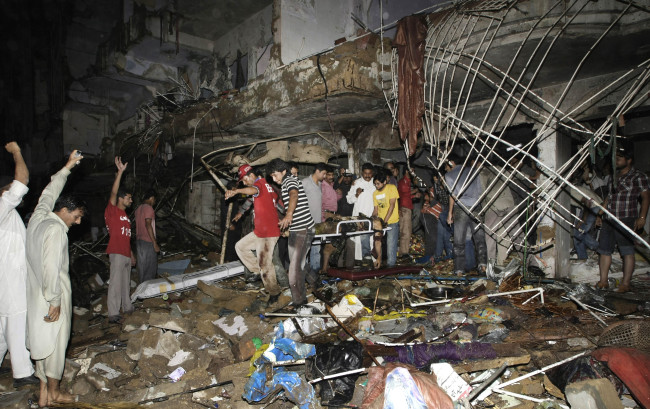 Pakistani medics carry the lifeless body of a man from the site of a bomb blast in Karachi, Pakistan, Sunday.   AP-Yonhap News