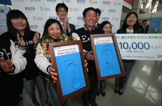 Park Ji-eun (left), the 10,000th volunteer of the Korea International Cooperation Agency, holds her commemorative footprint next to Yoon Jang-yong, the first volunteer, before her departure for Uzbekistan at Incheon International Airport on Tuesday. The 27-year-old was recruited last November.   Yonhap News