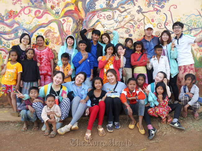 Students from Korea National University of Arts pose with children after painting school walls in Mondulkiri, Cambodia.   Korea National University of Arts