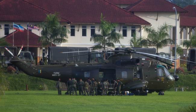 Officers stand by a Royal Malaysian Air Force Sikorsky S-61 helicopter in Cenderawasih, Malaysia, Tuesday.   AFP-Yonhap News
