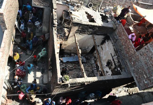Pakistani Christians gather around their burned out homes torched by Muslim demonstrators in Lahore on Sunday.   AFP-Yonhap News