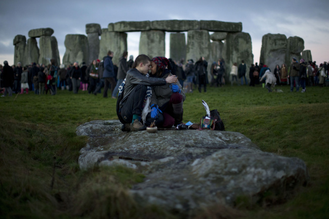People embrace by the ancient stone circle of Stonehenge, in southern England, as access to the site is given to druids, New Age followers and members of the public on the annual Winter Solstice, on Dec. 21, 2012.   AP-Yonhap News