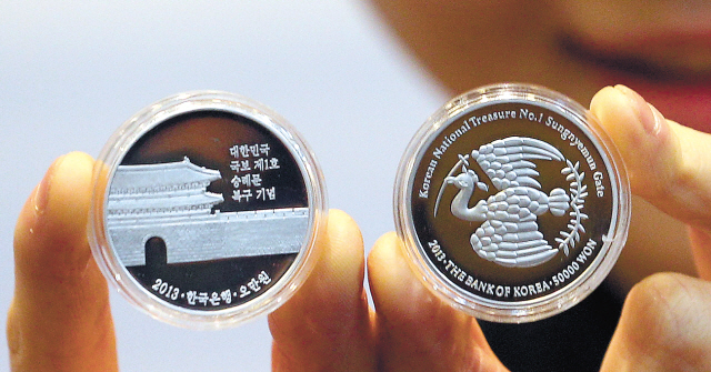 A model shows prototype commemoration coins for the upcoming
unveiling of Sungnyemun, which is national treasure No. 1,
at the Currency Museum of the Bank of Korea in Seoul on
Monday. (Yonhap News)