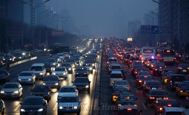 Traffic moves along a road at dusk in Beijing.   Bloomberg