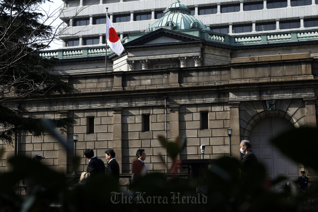 Pedestrians walk past the Bank of Japan headquarters in Tokyo.   Bloomberg