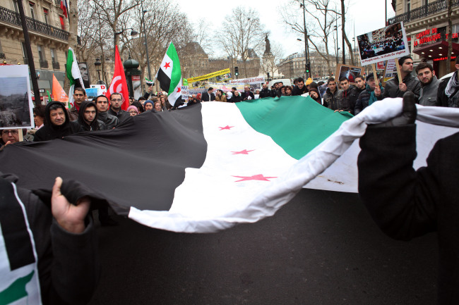 Demonstrators hold a giant Syrian flag during a march to mark the second anniversary of the revolt against Syrian President Bashar Assad’s government in Paris on Saturday.   AFP-Yonhap News