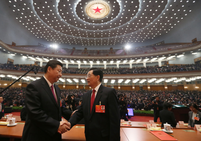 Xi Jinping (left) shakes hands with Hu Jintao at the closing meeting of the first session of the 12th National People’s Congress at the Great Hall of the People in Beijing on Sunday.   Xinhua-Yonhap News