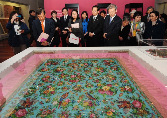 Guests at the National Museum's “The Peranakan World: Cross-cultural Art from Singapore and the Straits” look at a beadwork panel at the exhibitions opening ceremony on Monday.    Yonhap News