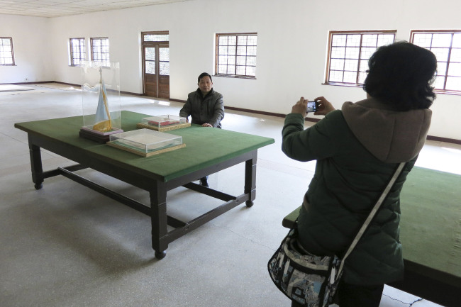 Chinese tourists take souvenir photos at tables, said to be where the original Armistice agreement was signed to halt the Korean War, at a museum hall in the Demilitarized Zone that separates the two Koreas at Panmunjeom, North Korea, Friday.   AP-Yonhap News