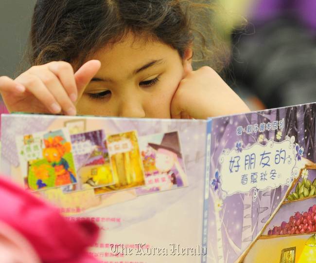 A student reads a book in Chinese during a second grade class at Broadway Elementary School, part of the city of Los Angeles’ public school system in Venice, California.   AFP-Yonhap News