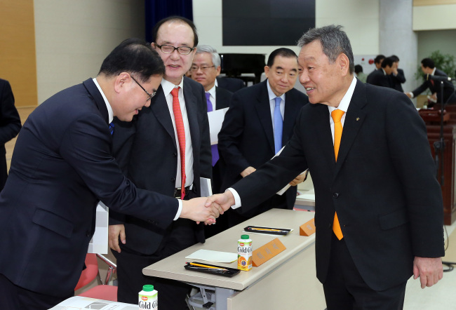 KB Financial Group chairman Euh Yoon-dae (right) shakes hands with outside directors after a shareholders’ meeting at the group’s headquarters in Seoul on Friday.   Yonhap News