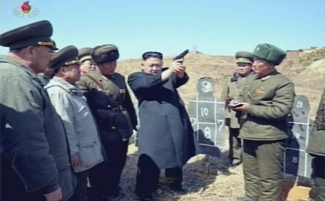North Korean leader Kim Jong-un points a gun into the air during his visit to Unit 1973 headquarters at an undisclosed location Friday in this footage run by the North’s official Korean Central TV on Saturday.   Yonhap News