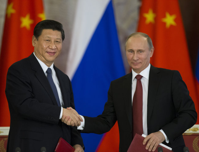 Russian President Vladimir Putin (right) and Chinese President Xi Jinping shake hands as they exchange documents after their talks in Moscow’s Kremlin on Friday.   AP-Yonhap News