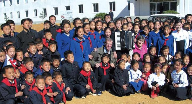 A handout photo taken on Oct. 25, 2011 shows Christopher Carpenter and Catherine Bertrand posing with students of a newly opened school in the Yonhung-ri, South Hwanghae Province, North Korea. (AFP-Yonhap News)