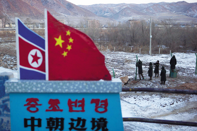 In this Dec. 8, 2012 file photo, Chinese paramilitary policemen build a fence near a concrete marker for the Chinese-North Korean border at a crossing in Tumen in eastern China’s Jilin province. (AP-Yonhap News)