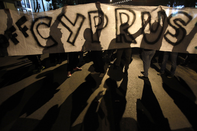 Protesters hold a banner that reads “Hands off Cyprus” during an anti-bailout rally on Sunday.  AP-Yonhap News