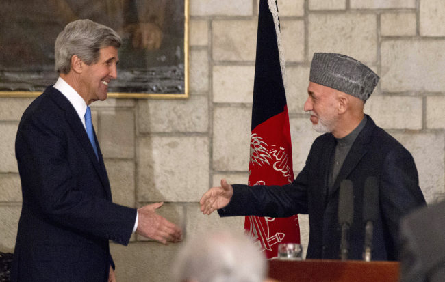 U.S. Secretary of State John Kerry reaches to shakes hands with Afghan President Hamid Karzai at the end of their joint news conference at the presidential palace in Kabul on Monday.   AP-Yonhap News
