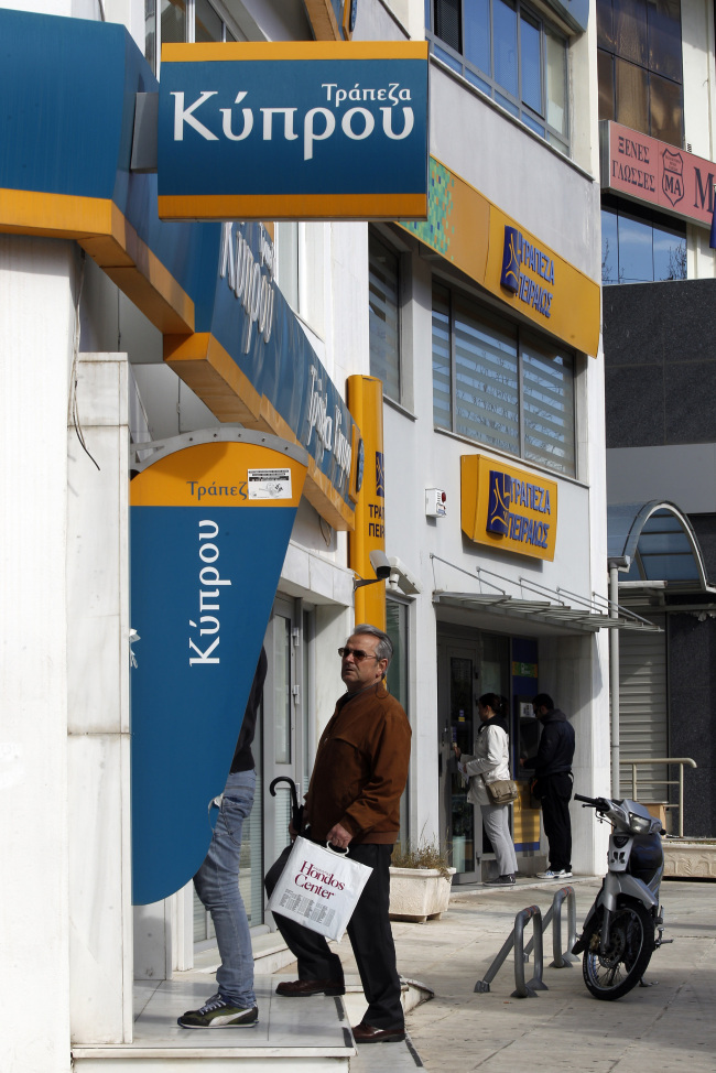 Customers use automated teller machines outside Bank of Cyprus in Athens on Tuesday.  Bloomberg