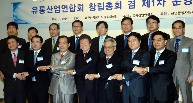 Former CEO of Homeplus Lee Seung-han (third from left, front row) joins hands with founding members of the council of retailers at a ceremony in Seoul on Wednesday. Lee was elected as co-chair of the new group.   Chung Hee-cho/The Korea Herald