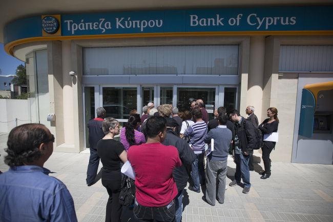 Customers queue outside a Bank of Cyprus Plc branch ahead of opening for the first time in two weeks in Nicosia, Cyprus, on Thursday, March 28, 2013. The Central Bank of Cyprus's capital controls will include a 300-euro ($383) daily limit on withdrawals and restrictions on transfers to accounts outside the country. Photographer: Simon Dawson/Bloomberg
Customers queue outside a Bank of Cyprus Plc branch ahead of opening in Nicosia, Cyprus, Thursday.  Bloomberg