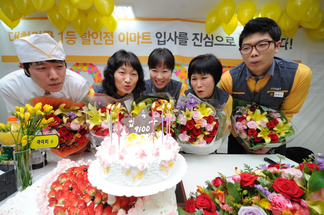 이마트는 1일 상품 진열 도급사원 9100명을 정규직으로 채용하고 이날 오전 서울 구로점에서 입사 환영식을 열었다. 정규직이 된 사원들이 활짝 웃으며 케이크 촛불을 끄고 있다. 구로점은 도급사원 100명을 정규직으로 전환했다. [사진제공=이마트]