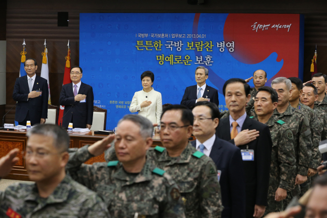 President Park Geun-hye, Prime Minister Chung Hong-won (second from left), Defense Minister Kim Kwan-jin (fourth from left) and other officials salute the national flag during the Defense Ministry’s policy briefing at Cheong Wa Dae on Monday.   Chung Hee-cho/The Korea Herald
