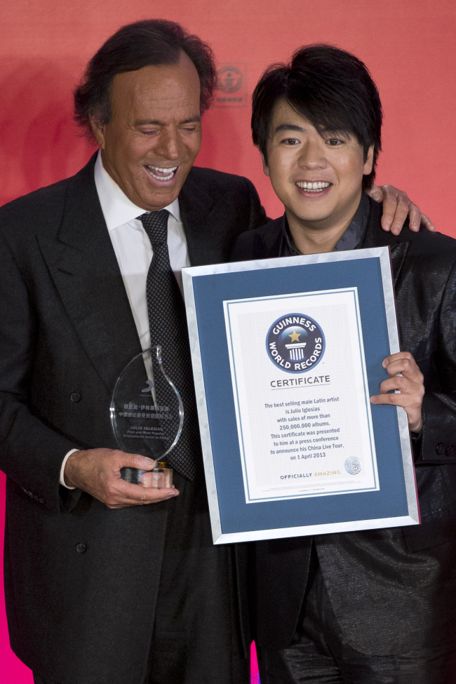 Spanish singer Julio Iglesias (left) and Chinese pianist Lang Lang pose for photos after Iglesias received the Guinness World Record for the best-selling male Latin artist in history and the First & Most Popular International Artist in China Award from Sony Music at a hotel in Beijing, China, on Monday.   AP-Yonhap News