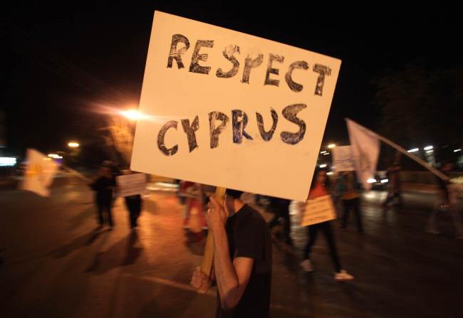 A Cypriot man holds a sign during a demonstration in Nicosia on Tuesday.    AFP-Yonhap News