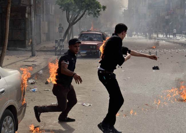 Egyptian Coptic Christians try to put out their burning clothes after they were attacked by unidentified individuals outside the cathedral in the central Cairo neighborhood of Abbassiya on Sunday.   AFP-Yonhap News