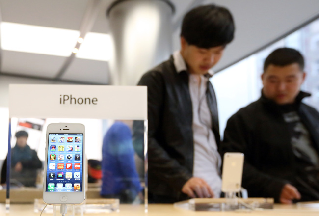 Customers try an Apple Inc. iPhone 5 at the store in the Wangfujing area of Beijing on March 12. Bloomberg
Customers try an Apple Inc. iPhone 5 at the store in the Wangfujing area of Beijing on March 12. Bloomberg