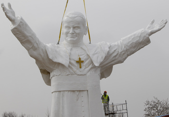 A worker adds finishing touches to a giant statue of the late Pope John Paul II being readied for unveiling this weekend in Czestochowa, Poland, Tuesday.   AP-Yonhap News