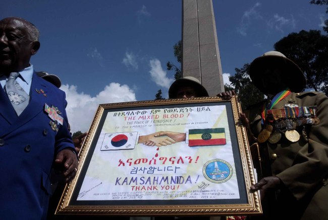 Ethiopian Korean War veterans hold a framed commemoration poster during an event held in Addis Ababa, Ethiopia, Saturday, to reenact Ethiopian troops’ departure for South Korea to fight the war.   Yonhap News