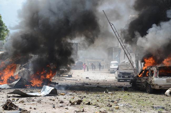 Cars burn in Mogadishu on Sunday, after a suicide bomber attack in the regional court premises that left several dead.   AFP-Yonhap News