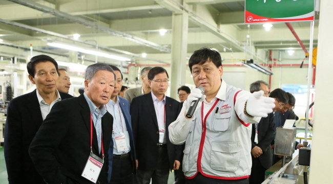LG Group chairman Koo Bon-moo (left, front) listens to an official from Mirae Korea during his visit to Mirae’s Cheonan factory, which makes TV frames for LG Electronics, on Thursday.   LG Group