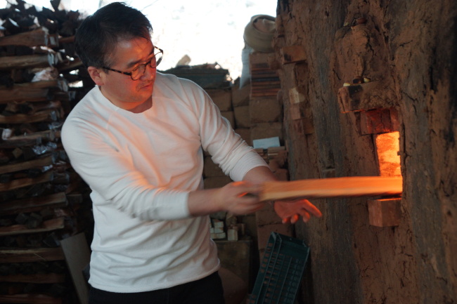 Ceramic artist Choi Jae-hun works at his kiln.