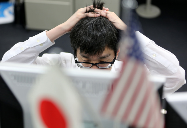 A dealer works behind U.S. and Japanese national flags at a foreign exchange brokerage in Tokyo, Japan, on Monday, April 22, 2013. The yen weakened, falling toward 100 per dollar for the first time since April 2009, after Bank of Japan Governor Haruhiko Kuroda said he was emboldened to press ahead with a campaign to defeat deflation. Photographer: Yuriko Nakao/Bloomberg
A dealer works at a foreign exchange brokerage in Tokyo on Monday.   Bloomberg
