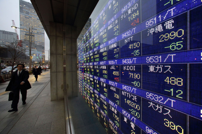Pedestrians walk past an electronic stock board outside a security firm in Tokyo.   Bloomberg