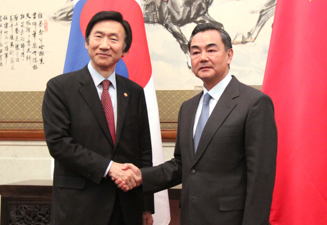 Foreign Minister Yun Byung-se shakes hands with his Chinese counterpart Wang Yi in Beijing on Wednesday. (Yonhap News)