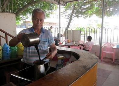 Huang Guanxin, 64, helps make coffee at his son’s coffee shop in Xinglong, Hainan. He used to take leave to pick coffee beans back in the 1960s.   The Straits Times