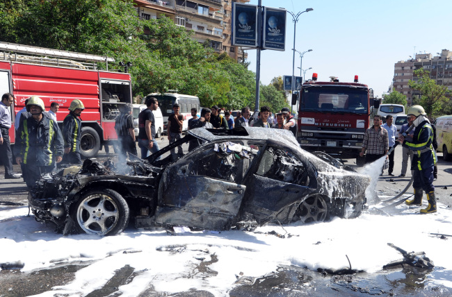 Syrian fire fighters extinguish burning cars after a car bomb exploded in the capital’s western neighborhood of Mazzeh, in Damascus, Syria, Monday.   AP-Yonhap News