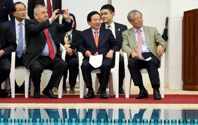 Cornel Marculescu (left, front row), executive director of the FINA Bureau and chief of its on-site evaluation team, and Gwangju Mayor Kang Un-tae (center) watch a local aquatic competiton at Yeomju Swimming Center in Gwangju on Monday.   Yonhap News